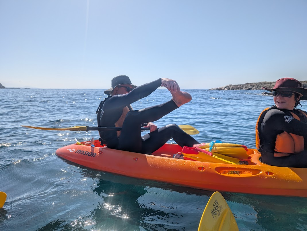 Photo of me in a sea kayak holding my right foot with my right hand.